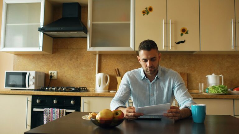 Person reviewing insurance papers beside a calculator and household inventory documents on a table.